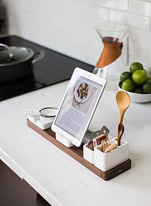 white tablet computer on white dock charger on top of white table inside dim-lit room thumbnail
