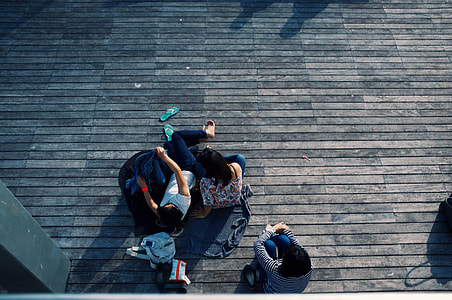 3 people sitting on brown wooden floor at daytime thumbnail