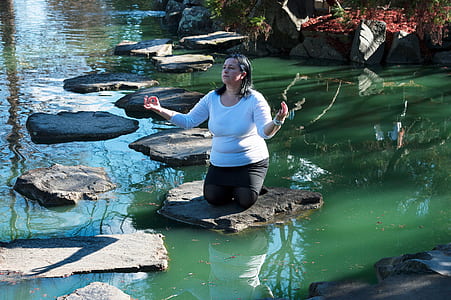 woman kneel down in the middle of pond thumbnail