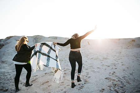 tilt-shift photography of two woman holding blanket thumbnail