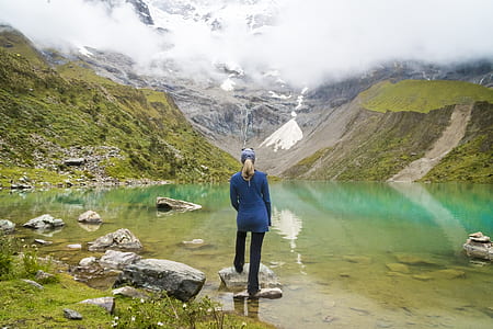 woman standing on gray rock near body of water at daytime thumbnail