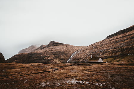 photography of brown house beside brown mountain during daytime thumbnail