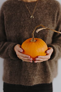 Women's hands in sweater are holding pumpkin thumbnail