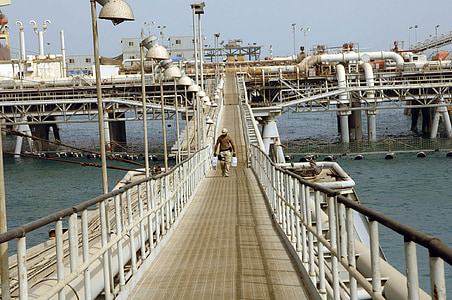 male walking on bridge carrying containers thumbnail