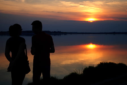 Silhouette of Man and Woman Near Water during Sun Set thumbnail