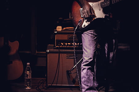 man on stage holding electric guitar thumbnail