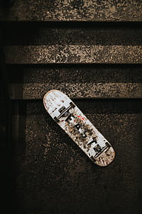 turned over white and black skateboard on brown staircare thumbnail
