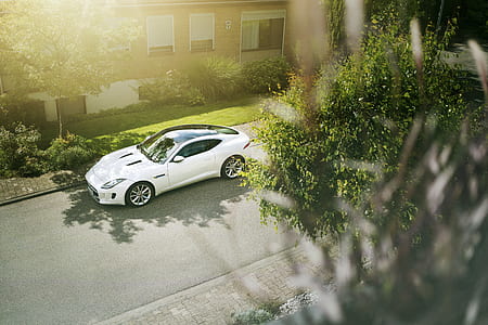 white sports coupe parked on side of road during day time thumbnail