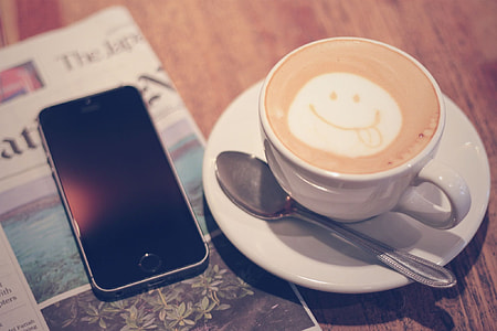 space gray iPhone 5s beside white ceramic teacup with latte thumbnail