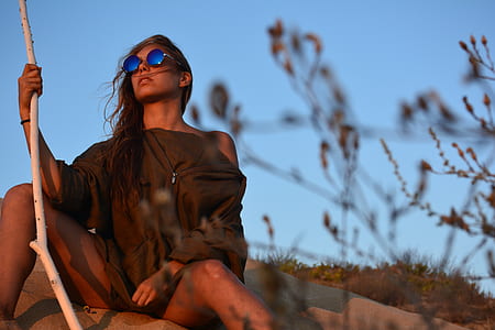 woman in brown top sitting on gray rock formation thumbnail