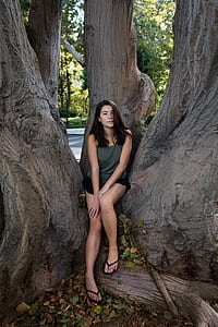 woman in gray top and black short shorts sitting beside tree thumbnail