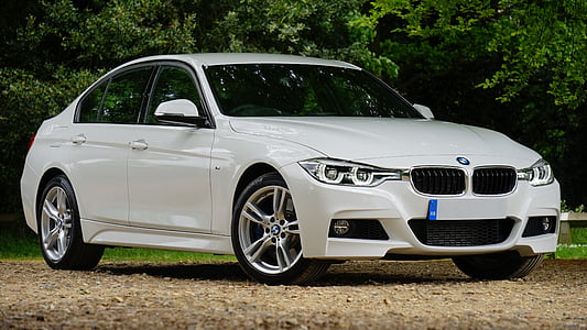 white BMW sedan on brown surface near green trees thumbnail