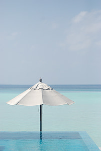white and black patio umbrella on body of water thumbnail