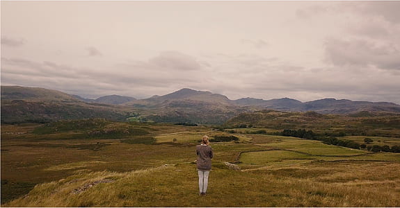 woman standing on cliff under blue sky during daytime thumbnail