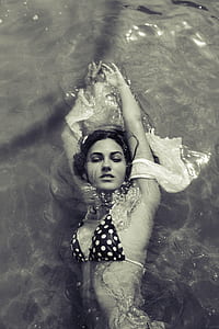 woman wearing black and white bra swimming on water thumbnail
