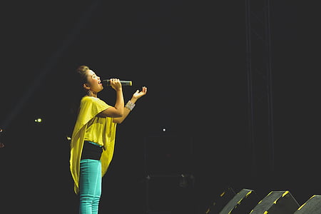 woman in yellow top singing on stage thumbnail
