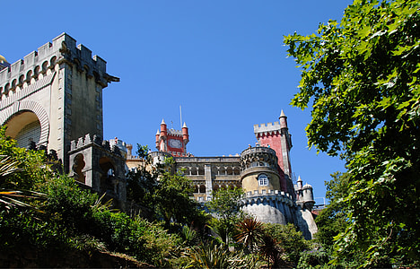 photo of beige and red castle with green plants and trees during day time thumbnail