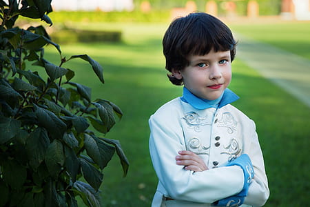 selective focus photography of boy standing near green leaf plant thumbnail