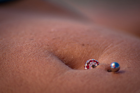silver-colored piercing on person naval thumbnail