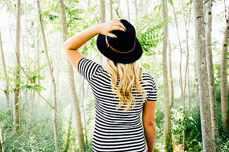 woman in black and white striped shirt wearing black cap standing in a forest thumbnail