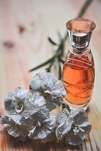 white flowers beside clear glass spray bottle on brown wooden desk thumbnail