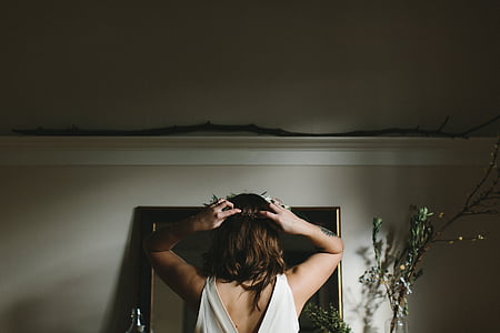 woman standing in front of mirror inside room thumbnail