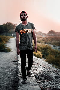 Man in Gray Shirt Standing on Concrete Pathway thumbnail
