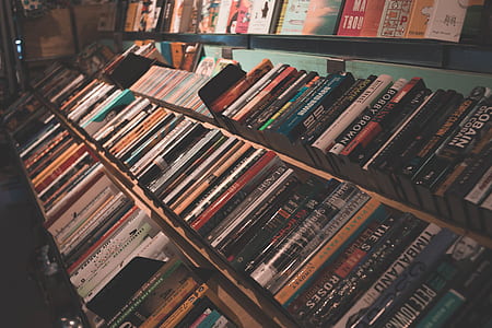 softbound books on brown and black shelf thumbnail