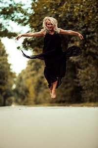 woman wearing black sleeveless long dress while leaping thumbnail