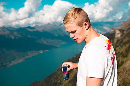 selective focus photography of man holding Red Bull can thumbnail