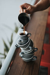 person pouring coffee on white stacked teacups thumbnail