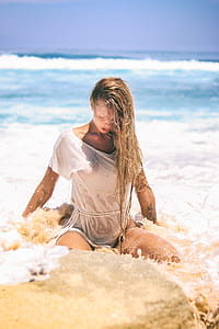 selective focus woman sitting on seashore during daytime thumbnail