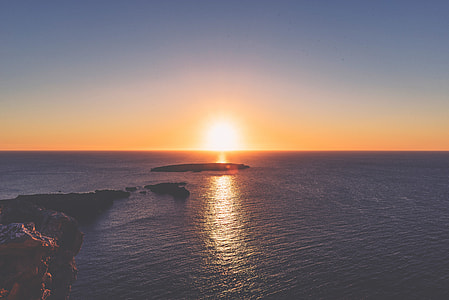 landscape photography of island surrounded by calm seas during golden hour thumbnail