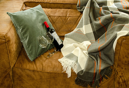 liquor bottle and two red wine glasses on sofa thumbnail