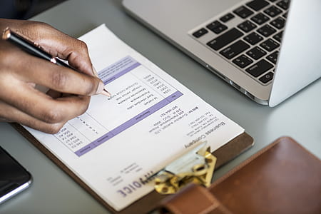 person writing on paper near laptop thumbnail