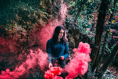 Woman Wearing Blue Long Sleeved Shirt Standing On Pink Smoke thumbnail