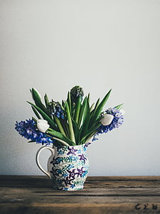 blue hyacinths and white tulips in flower vase on brown wooden surface thumbnail