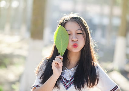Woman Holding Green Leaf With Lips Kissing and Closing Eyes thumbnail