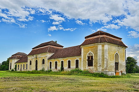 yellow, white, and brown concrete building under white and blue cloudy sky at daytime thumbnail