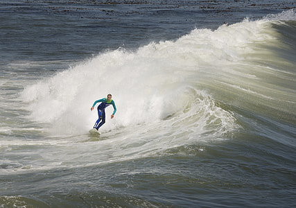 man wearing wetsuit standing on surfboard during daytime thumbnail