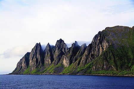 brown and green mountain beside body of water thumbnail