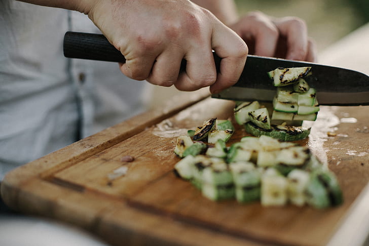 selective focus photo of person slicing vegetable