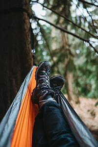 Person Wearing Pair of Black Hiking Shoes Lying on Orange and Gray Hammock thumbnail