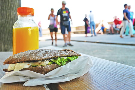 burger and plastic bottle on table near people passing by thumbnail