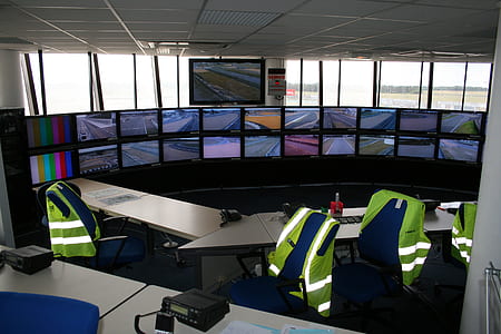 flat screen computer monitors on table with rolling chairs inside room thumbnail