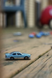 selective focus photography of blue coupe scale model on brown wooden surface thumbnail