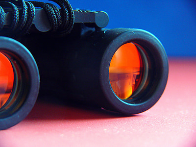 selective focus photography of black and orange binoculars on pink surface thumbnail