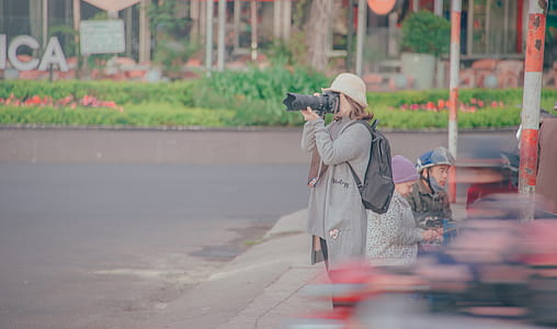 Woman Holding Black Dslr Camera Taking Picture thumbnail