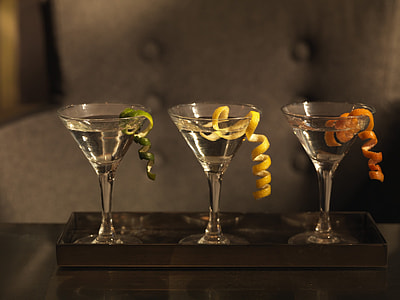 three martini glasses with white liquid and fruit peel garnishing thumbnail