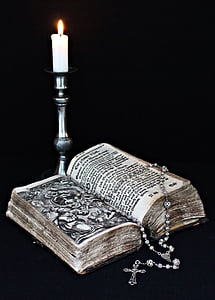 book with gray rosary on top beside silver candle holder thumbnail